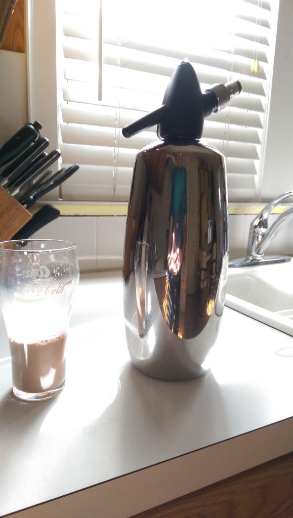 An old style Coca~Cola glass with a 1/4 Cup of 2% milk and 1 Tablespoon of syrup mixed up and waiting for a top off of seltzer